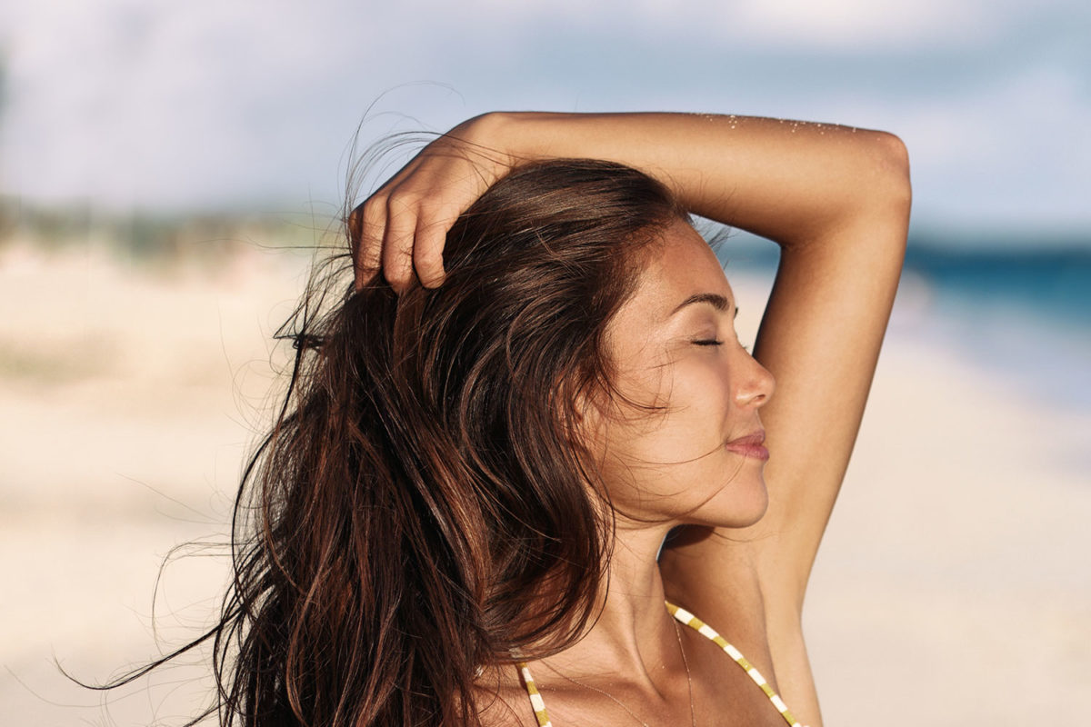 10 Tips for Summer Oily Skin. Photo of young woman on beach in the sun.